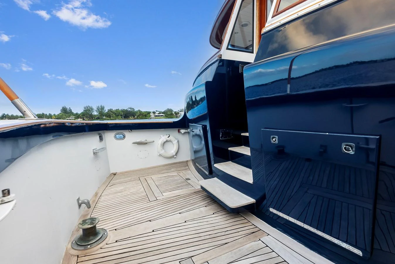 The aft deck features elegant teak flooring and polished navy blue accents, offering a refined outdoor space. aboard CHANTICLEER Yacht for Sale