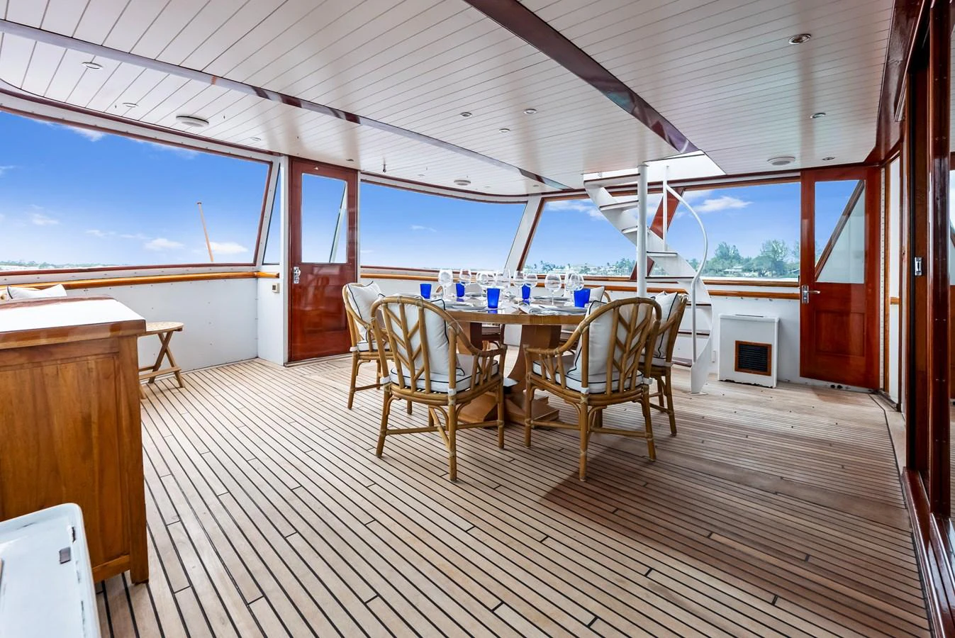 The aft deck features a spacious dining area with elegant wooden furniture and panoramic views. aboard CHANTICLEER Yacht for Sale