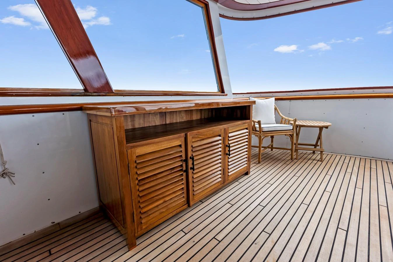 A serene salon area featuring wooden cabinetry and a comfortable seating arrangement with a view of the sky. aboard CHANTICLEER Yacht for Sale