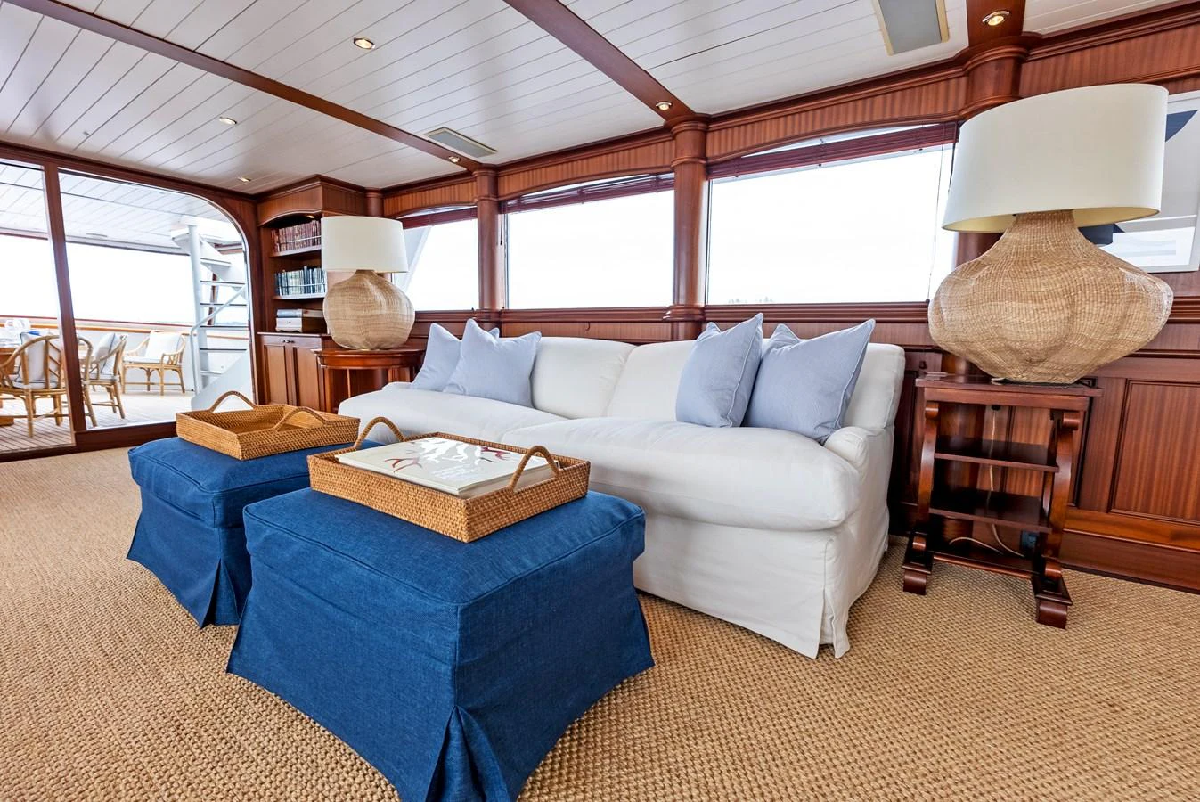The salon features a comfortable white sofa with blue ottomans and large wicker lamps, creating a cozy and inviting atmosphere. aboard CHANTICLEER Yacht for Sale