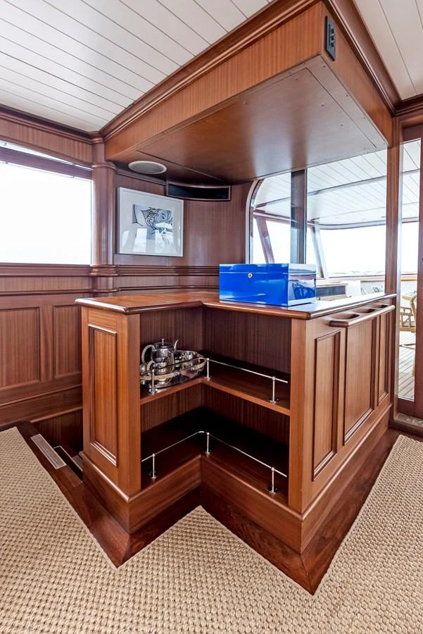 The image showcases a beautifully crafted wooden interior with a built-in bar area. aboard CHANTICLEER Yacht for Sale