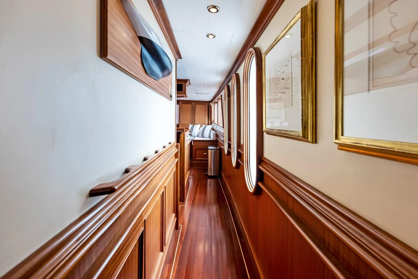 A beautifully crafted hallway with rich wood paneling and elegant artwork leads to a cozy seating area. aboard CHANTICLEER Yacht for Sale