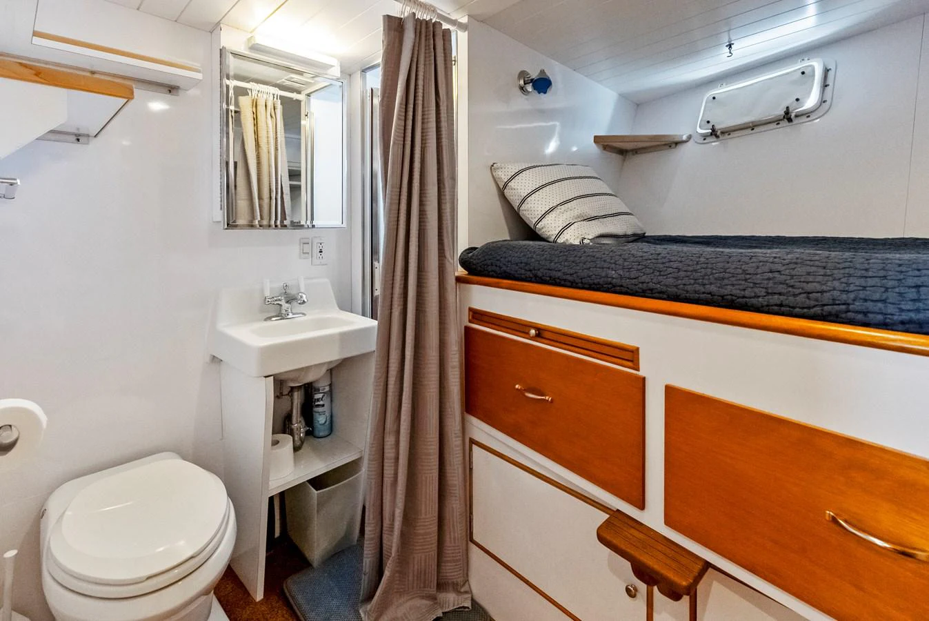 The yacht's bathroom features a compact and functional design with a sink, toilet, and a cozy sleeping area above storage cabinets. aboard CHANTICLEER Yacht for Sale