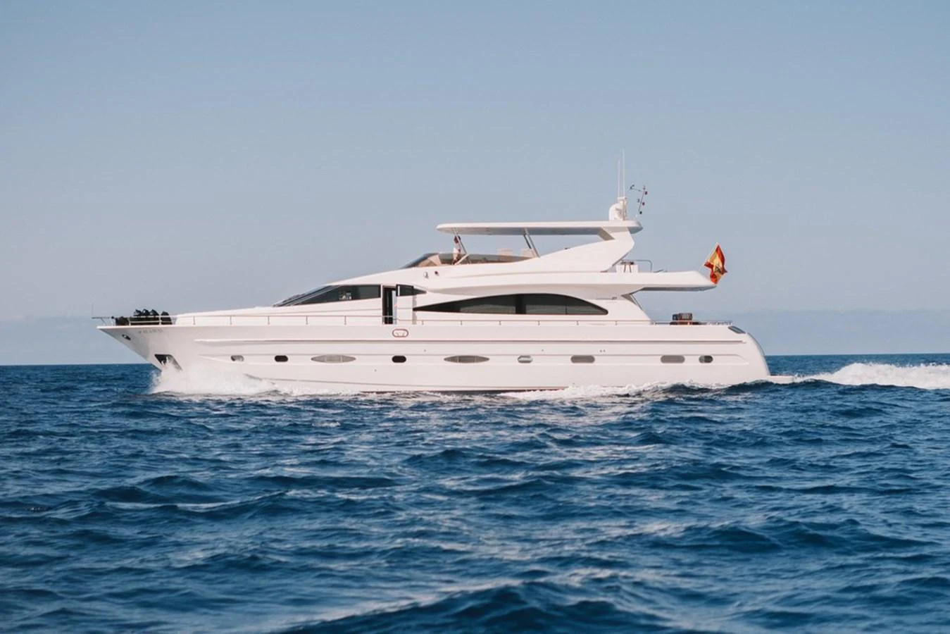 A sleek white yacht glides smoothly over the blue ocean waters under a clear sky. aboard ASTONDOA 82 GLX Yacht for Sale
