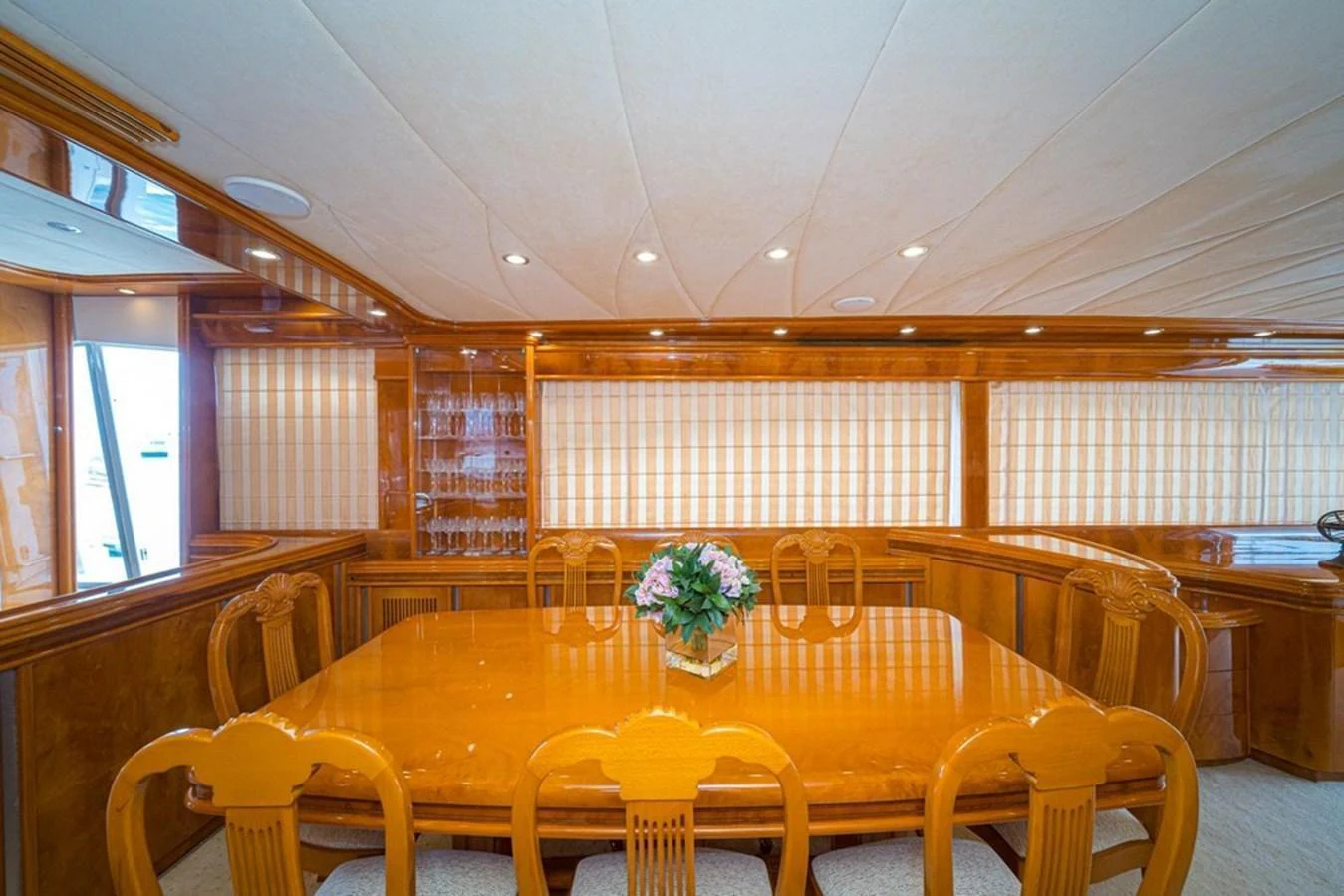 The yacht's dining area features a polished wooden table with elegant chairs and a floral centerpiece. aboard ASTONDOA 82 GLX Yacht for Sale