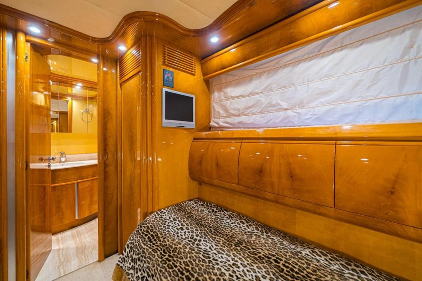 The guest cabin features warm wood finishes and a cozy bed with a leopard print cover. aboard ASTONDOA 82 GLX Yacht for Sale