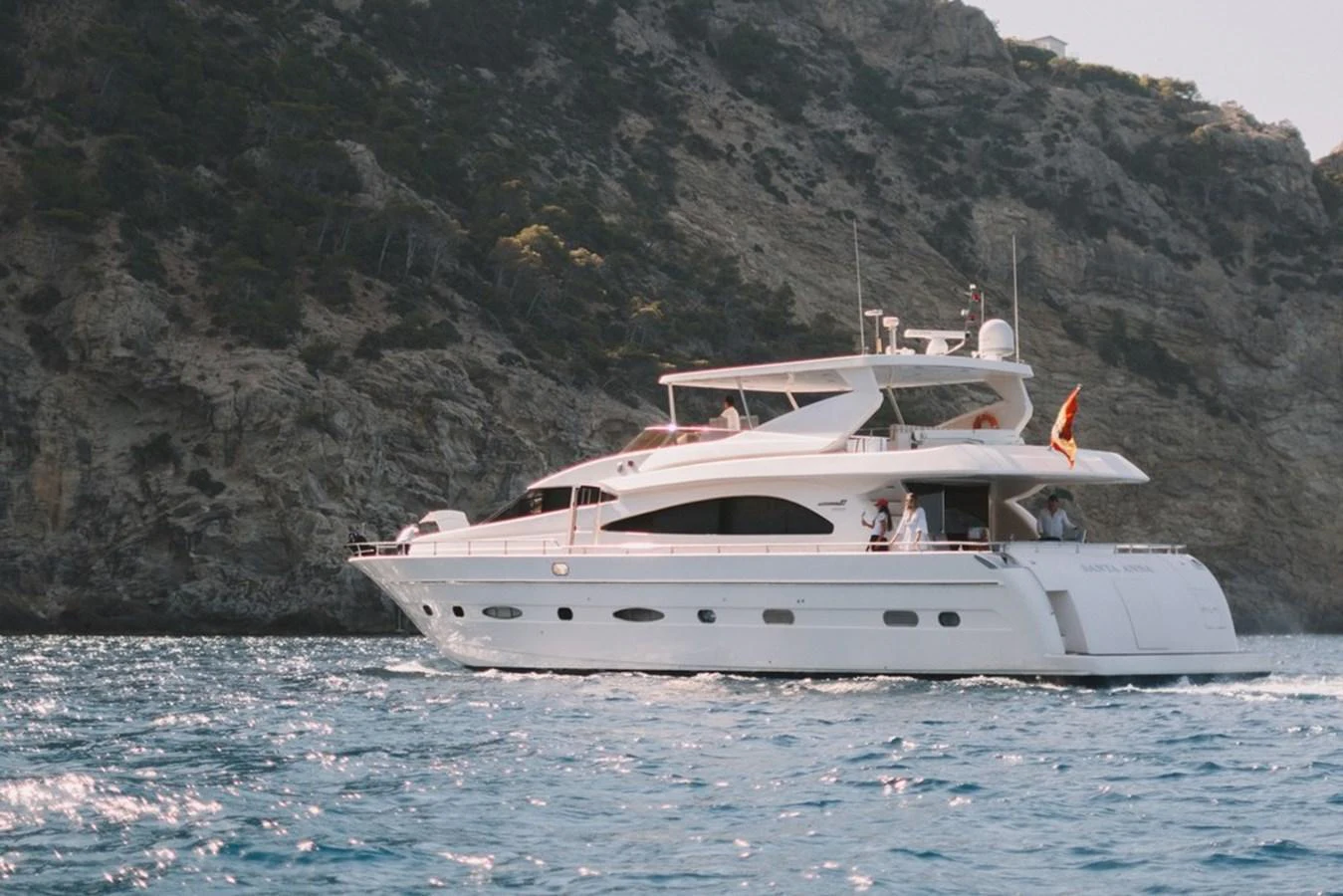 A luxurious yacht cruises along a scenic coastline with rugged cliffs in the background. aboard ASTONDOA 82 GLX Yacht for Sale