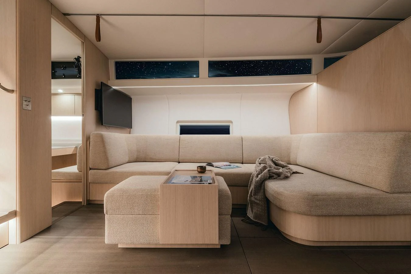 The salon features a cozy and modern seating area with a neutral color palette, perfect for relaxation. aboard 2026 YYACHTS Y7 Yacht for Sale