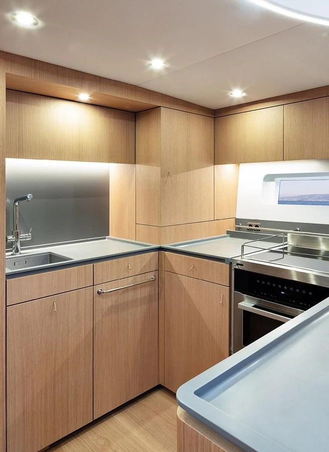The yacht's galley features modern appliances and sleek wooden cabinetry, creating a functional and stylish cooking space. aboard 2026 YYACHTS Y7 Yacht for Sale