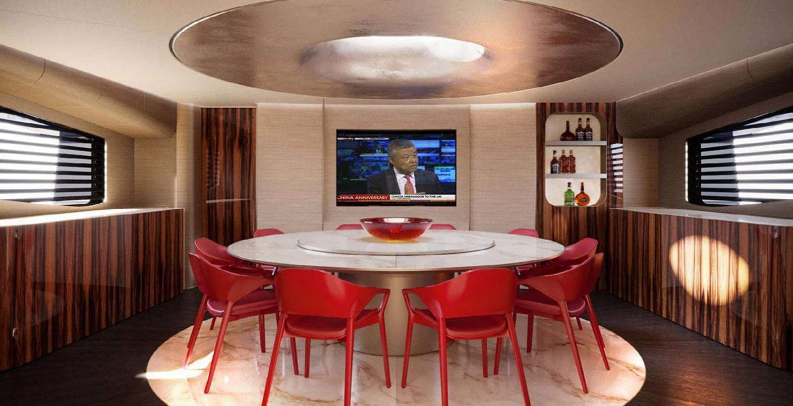 The yacht's dining area features a modern design with a round table and vibrant red chairs, complemented by a built-in entertainment system. aboard T-EVO 120 Yacht for Sale