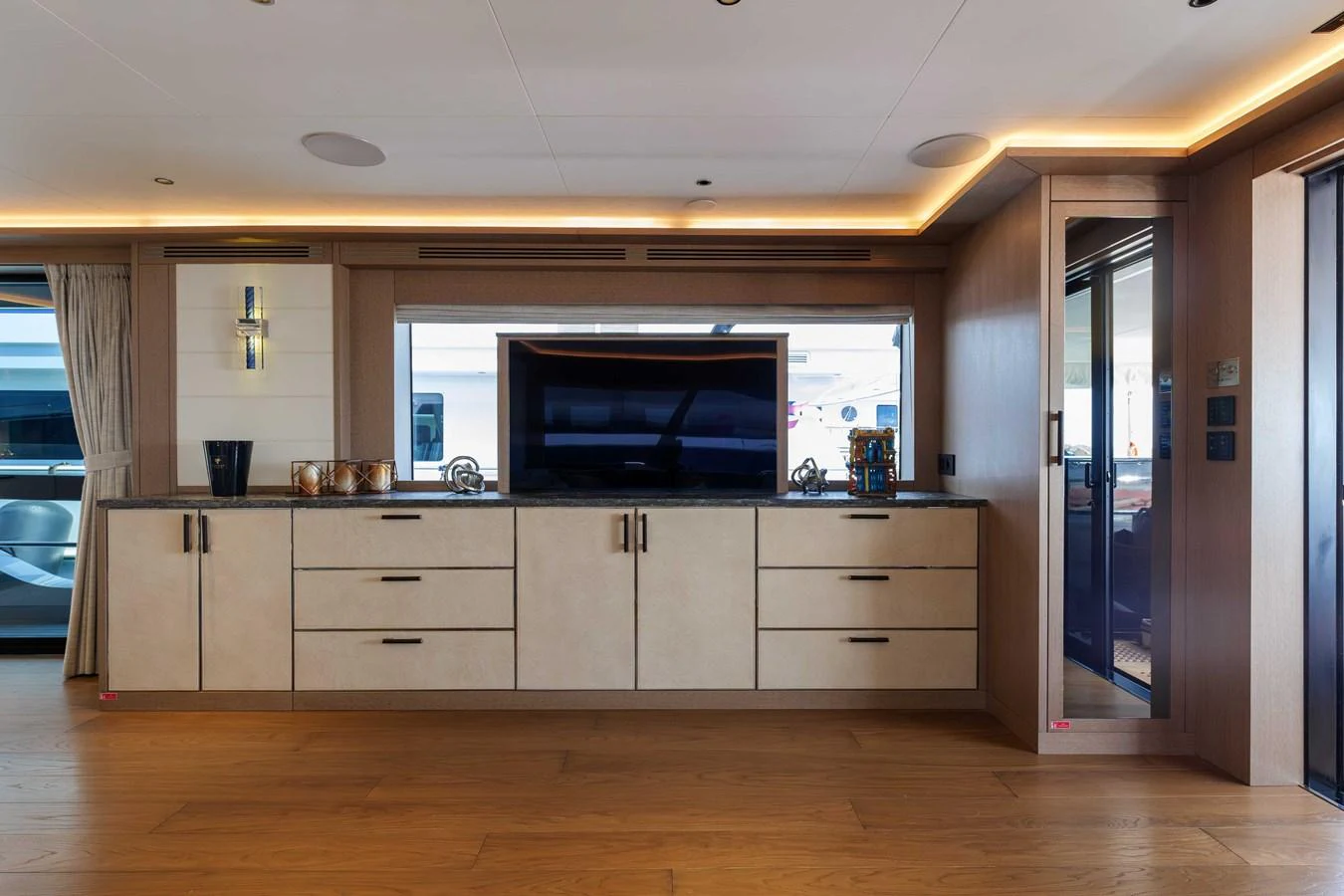 The yacht's interior features a modern entertainment area with a large flat-screen TV and ample storage cabinets. aboard 2024 SIRENA 88 Yacht for Sale