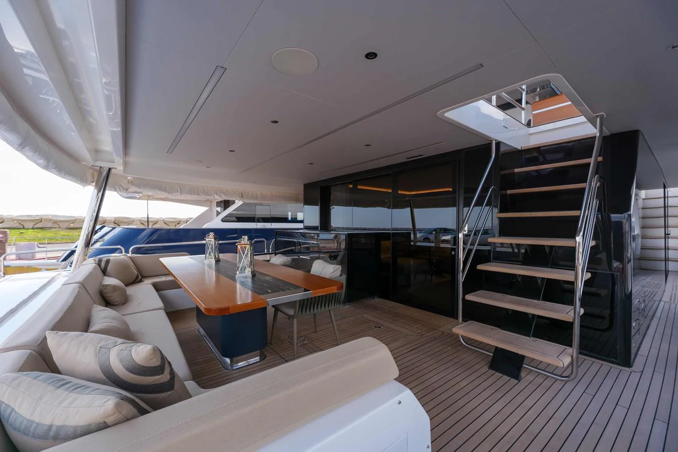 The aft deck features a spacious seating area with a dining table and easy access to the upper deck via a sleek staircase. aboard 2024 SIRENA 88 Yacht for Sale