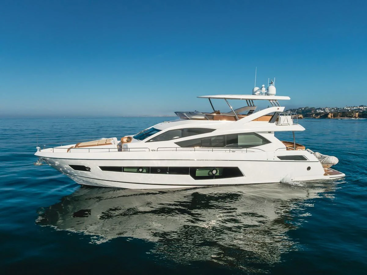 A sleek and modern yacht glides gracefully on calm waters under a clear blue sky. aboard AGUA RANCHO Yacht for Sale