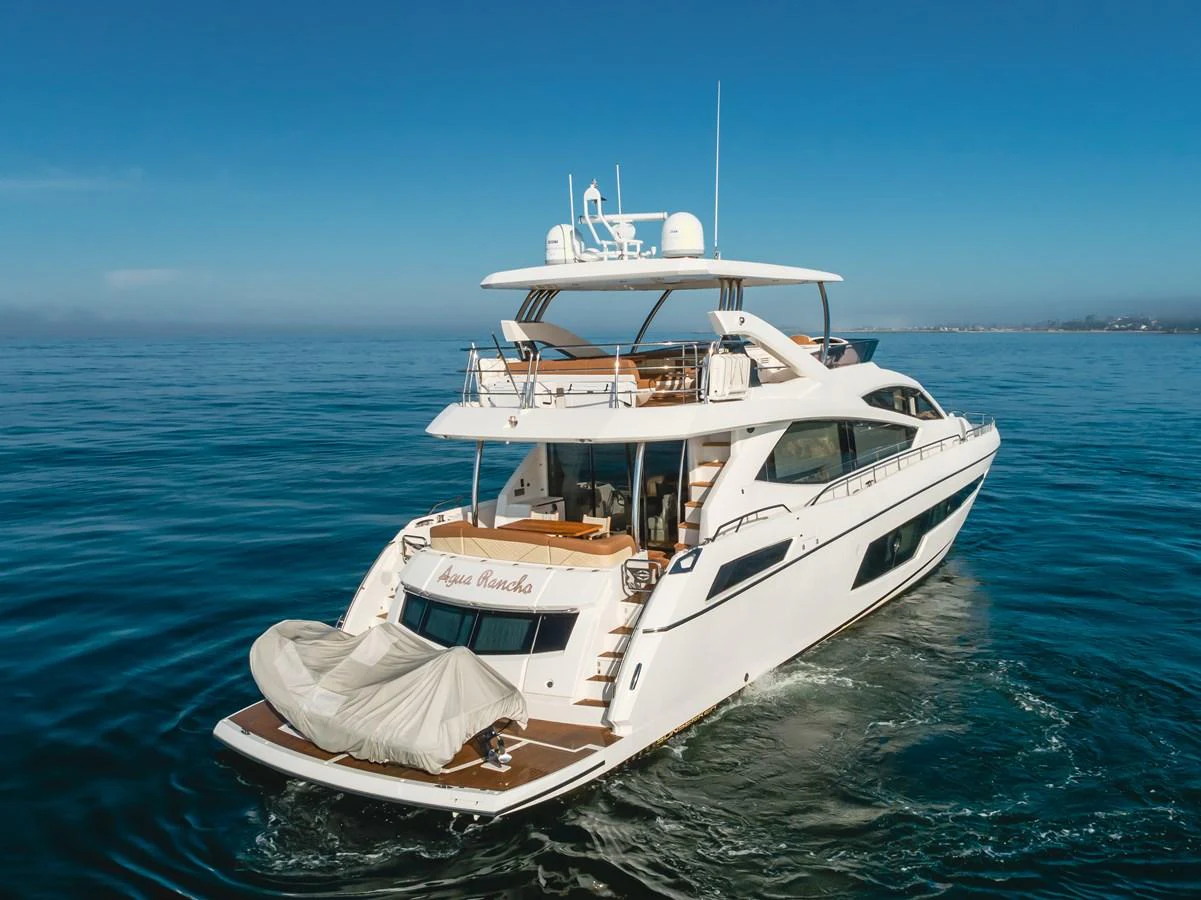 A luxurious yacht glides gracefully on calm waters under a clear blue sky. aboard AGUA RANCHO Yacht for Sale