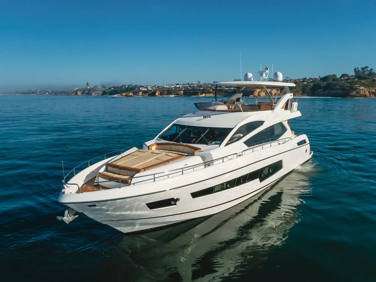 A sleek and modern yacht cruises gracefully on calm waters with a scenic coastal backdrop. aboard AGUA RANCHO Yacht for Sale