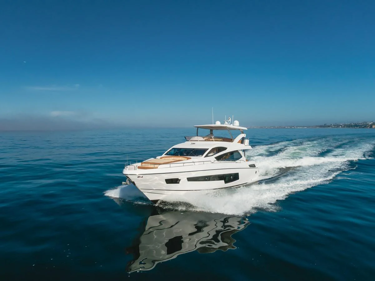 A sleek yacht cruises swiftly on calm blue waters under a clear sky. aboard AGUA RANCHO Yacht for Sale