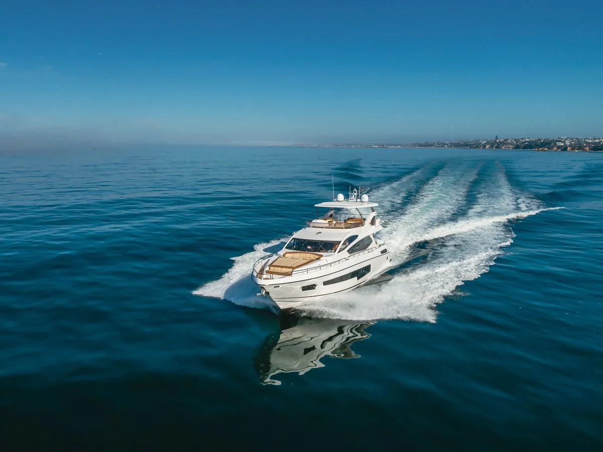A sleek yacht cruises swiftly across calm waters under a clear blue sky. aboard AGUA RANCHO Yacht for Sale