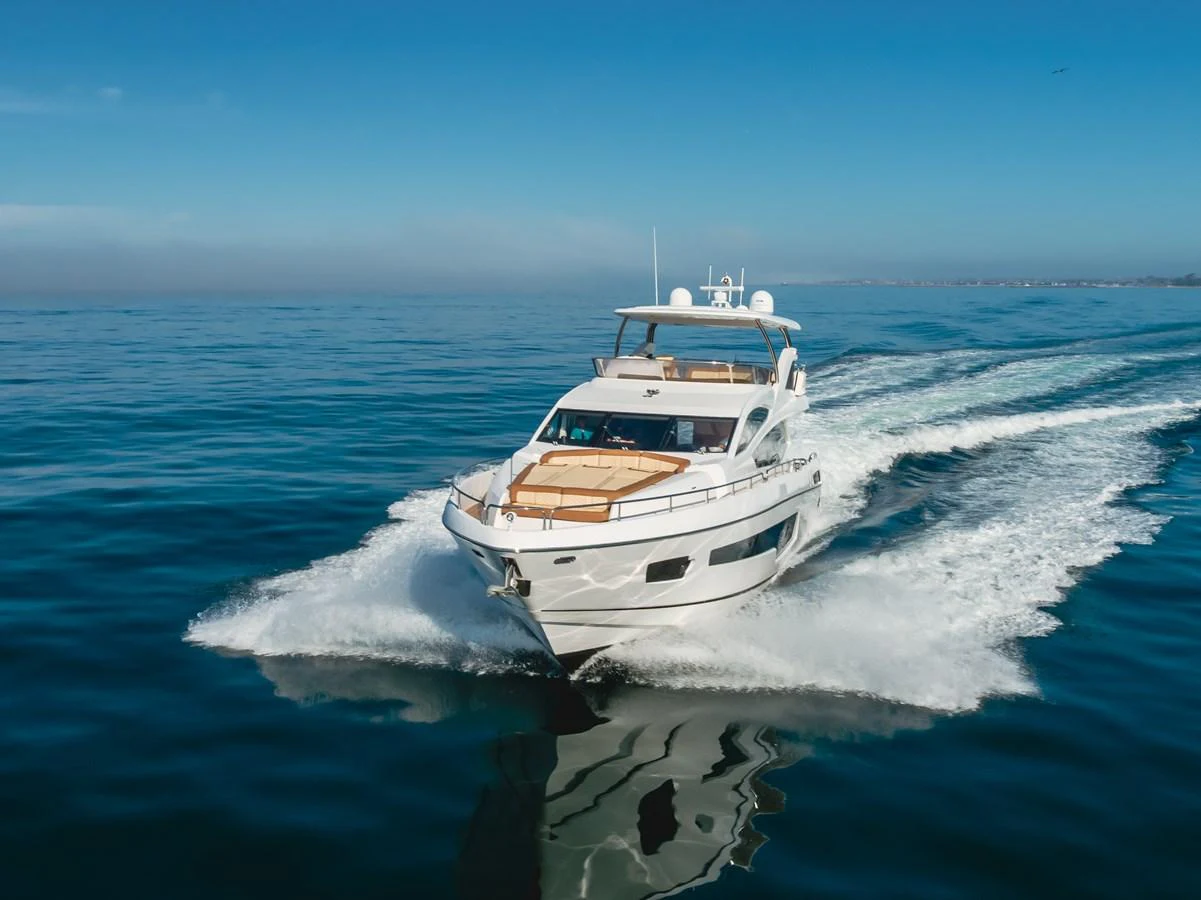 A sleek yacht cruises swiftly through calm waters under a clear blue sky. aboard AGUA RANCHO Yacht for Sale