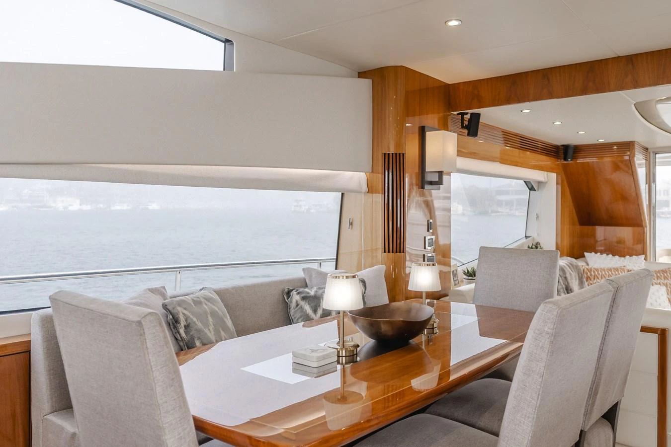 The yacht's dining area features a sleek wooden table surrounded by comfortable upholstered chairs, with large windows offering a scenic view. aboard AGUA RANCHO Yacht for Sale