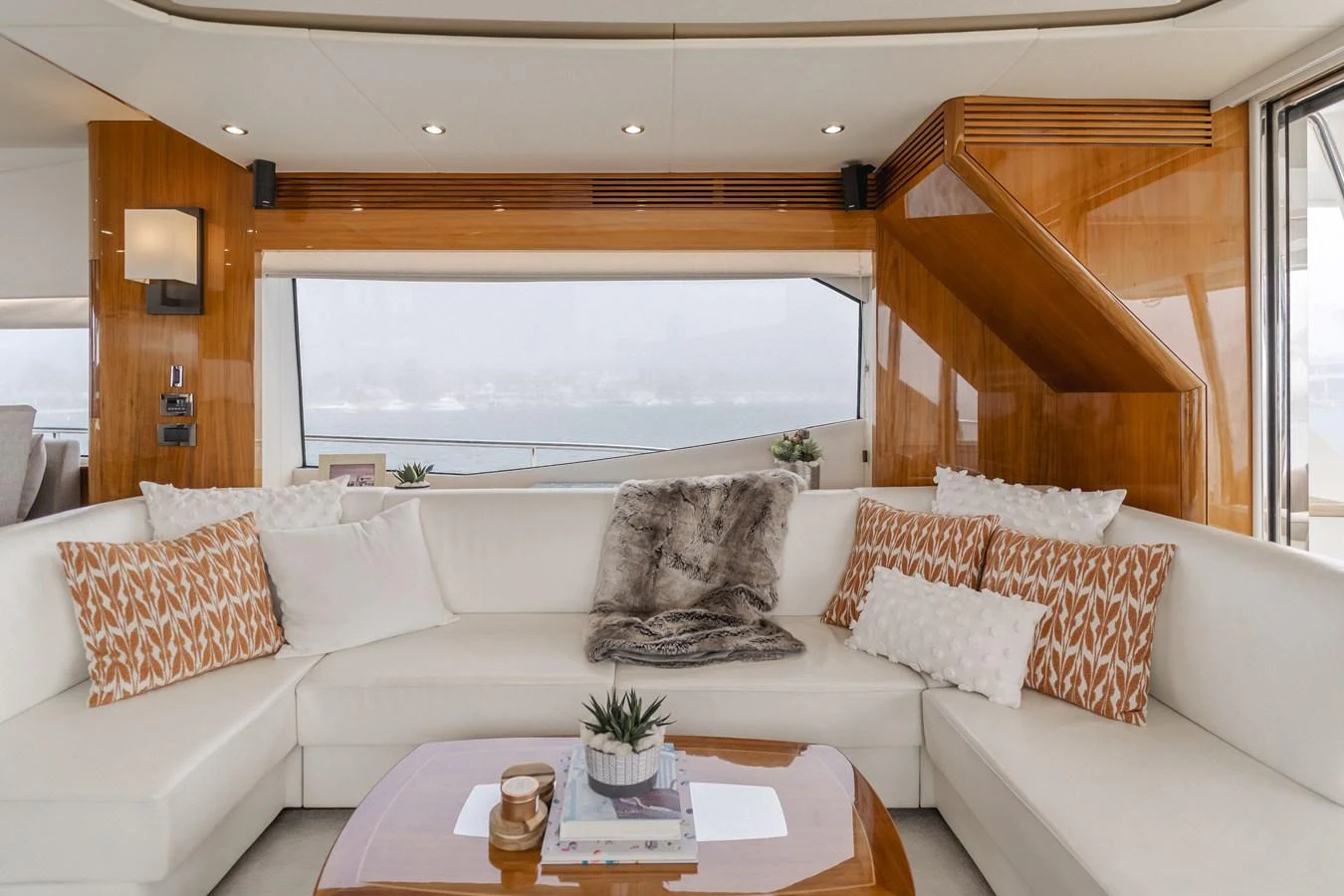The salon features a plush L-shaped sofa with elegant decor and panoramic windows. aboard AGUA RANCHO Yacht for Sale