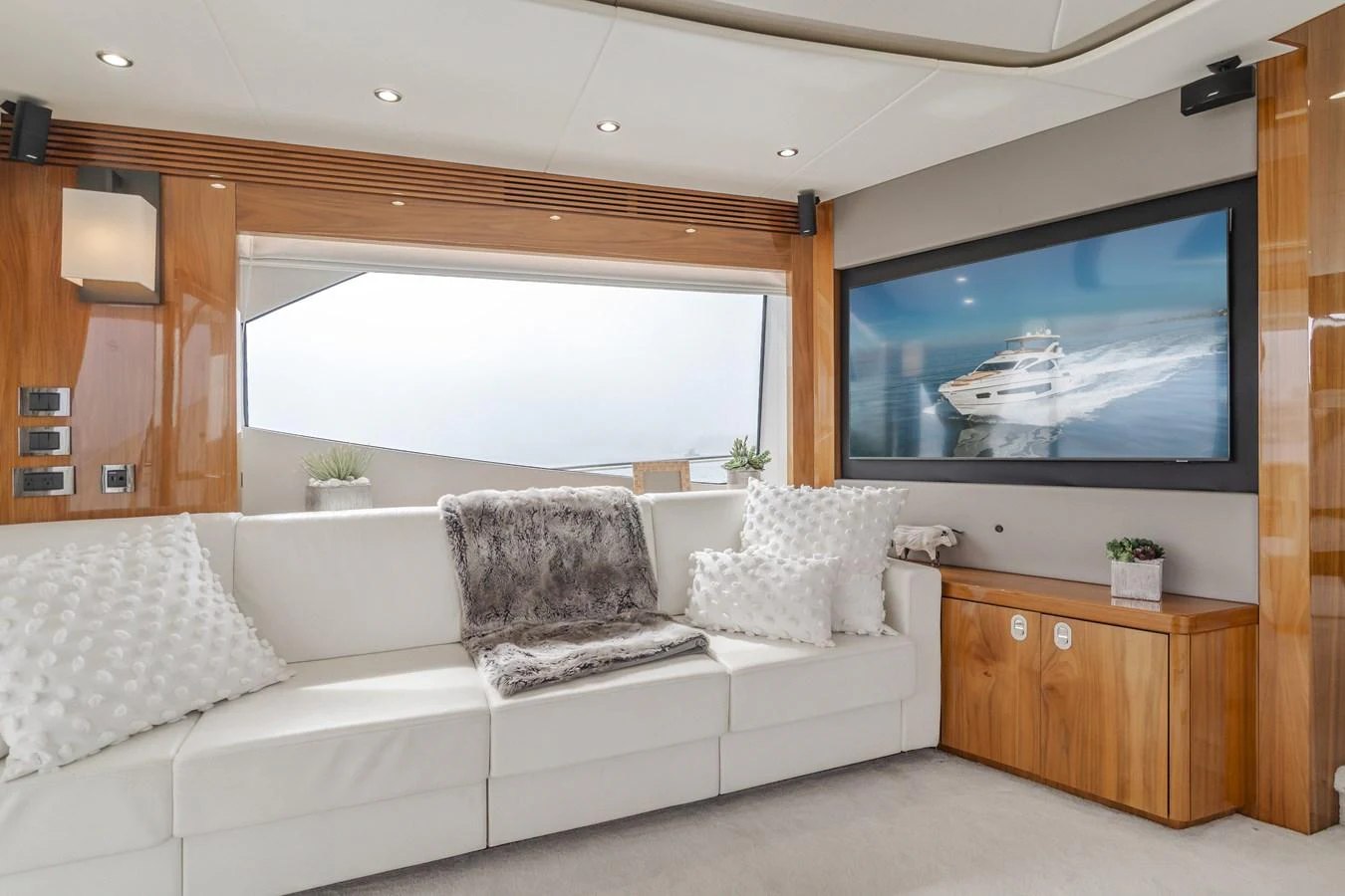 The salon features a plush white sofa with elegant wooden accents and a large flat-screen TV. aboard AGUA RANCHO Yacht for Sale