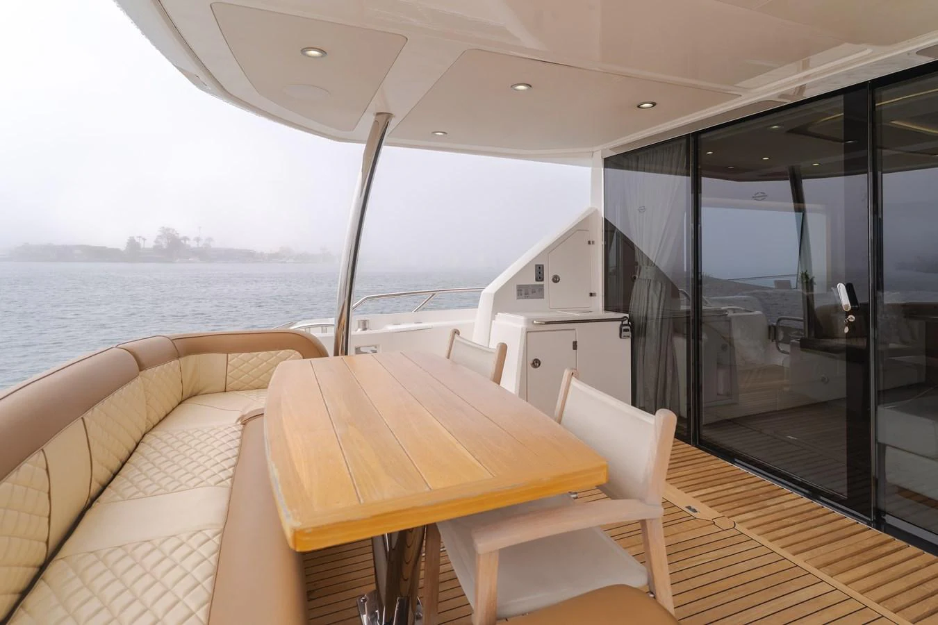 The aft deck features a comfortable dining area with a wooden table and cushioned seating, perfect for enjoying meals with a view of the water. aboard AGUA RANCHO Yacht for Sale