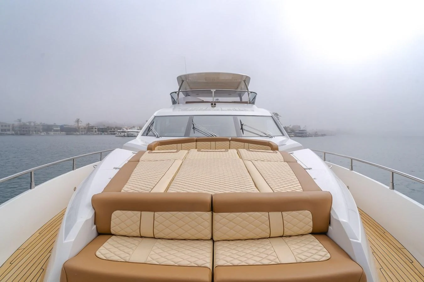 The yacht's foredeck features luxurious sun pads with a serene waterfront backdrop. aboard AGUA RANCHO Yacht for Sale