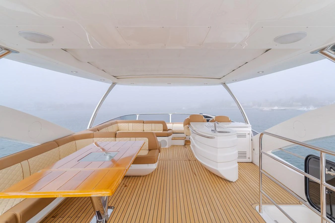 The flybridge features a spacious seating area with a dining table and a sleek bar counter, perfect for entertaining. aboard AGUA RANCHO Yacht for Sale