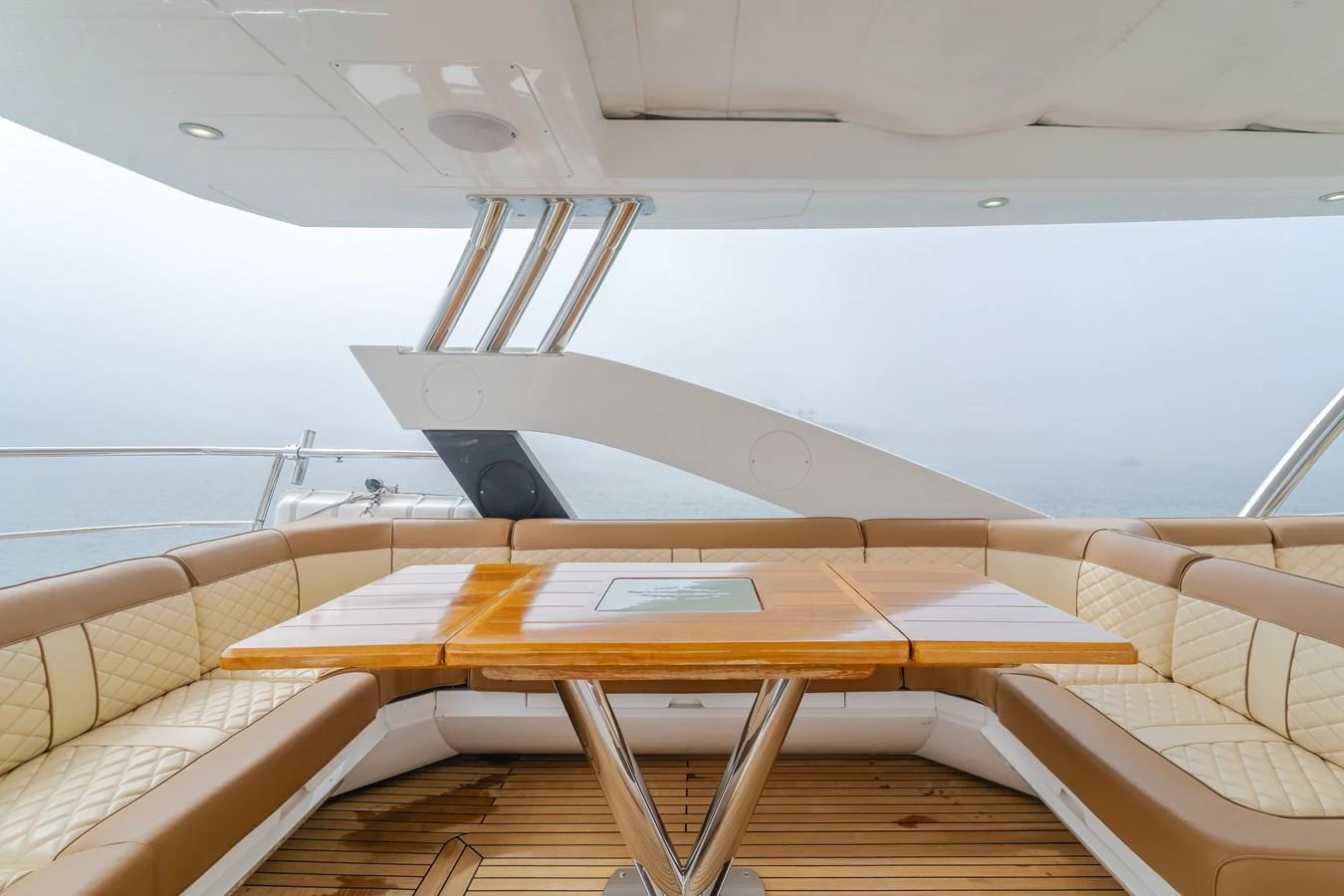 The aft deck features a spacious and elegant seating area with a polished wooden table, perfect for outdoor dining and relaxation. aboard AGUA RANCHO Yacht for Sale