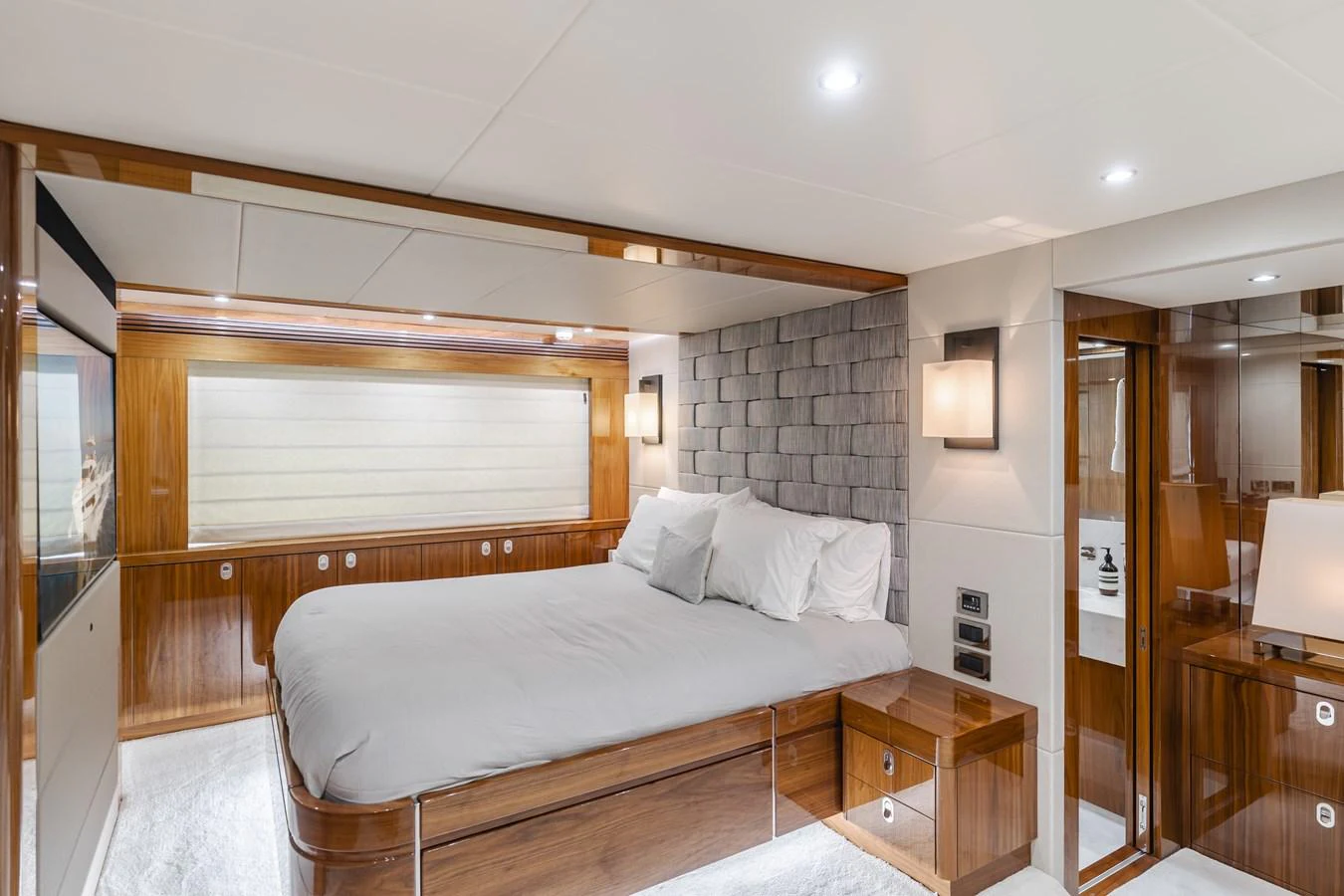 The master stateroom features a luxurious bed with elegant wood paneling and modern lighting. aboard AGUA RANCHO Yacht for Sale