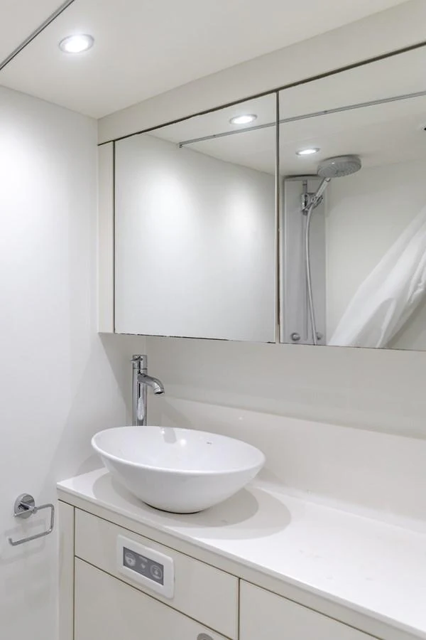 A sleek and modern yacht bathroom with a stylish vessel sink and mirrored cabinets. aboard AGUA RANCHO Yacht for Sale