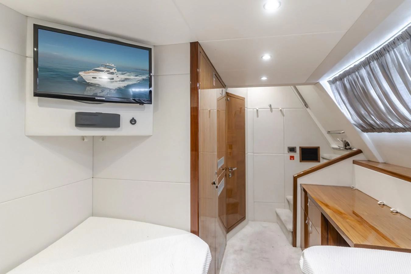 A cozy cabin featuring a wall-mounted TV, wooden accents, and a small desk area. aboard AGUA RANCHO Yacht for Sale