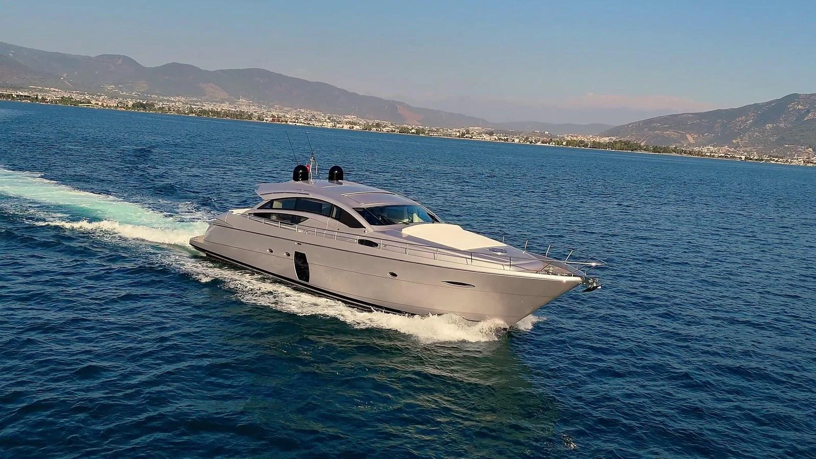 A sleek yacht cruises through calm waters with a scenic coastline in the background. aboard FREEDOM 2 Yacht for Sale