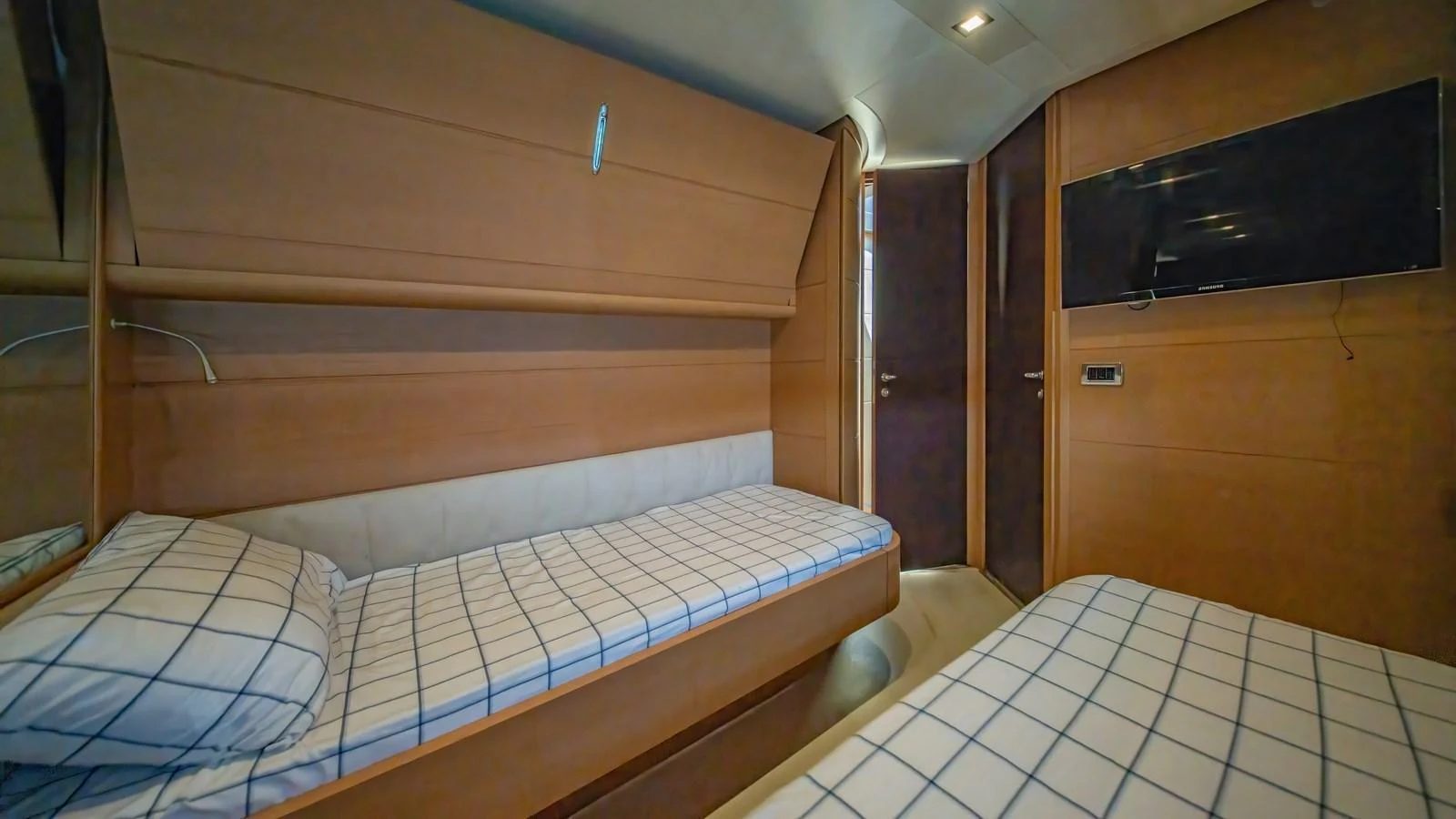 The guest cabin features twin beds with checkered bedding and a wall-mounted TV for comfort and entertainment. aboard FREEDOM 2 Yacht for Sale