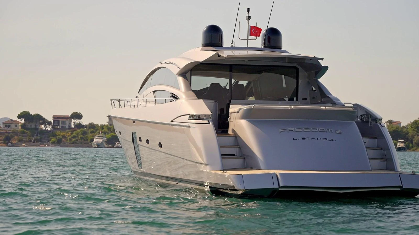 A sleek and modern yacht cruising on calm waters with a scenic coastal backdrop. aboard FREEDOM 2 Yacht for Sale