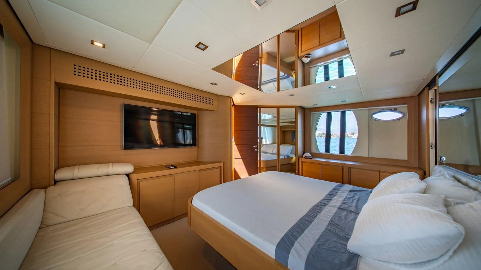 The stateroom features a luxurious bed, a flat-screen TV, and ample natural light through round windows. aboard FREEDOM 2 Yacht for Sale