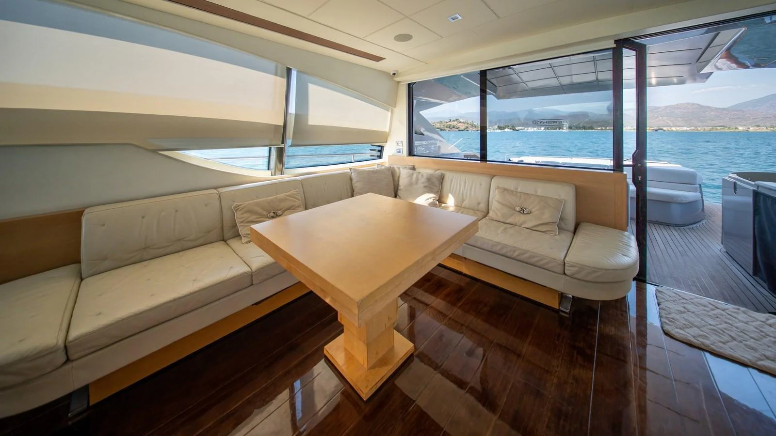 The salon features a spacious seating area with a large wooden table and panoramic views through large windows. aboard FREEDOM 2 Yacht for Sale