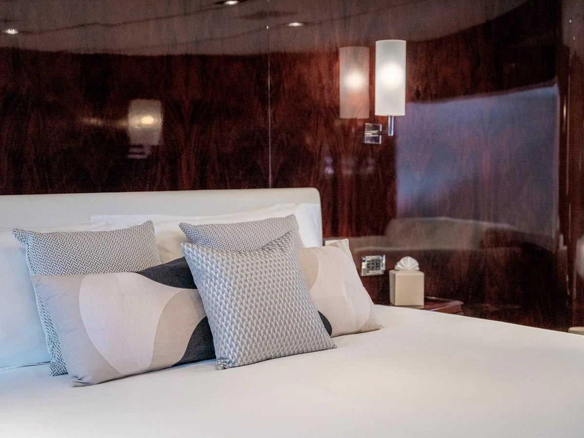 The stateroom features a plush bed with elegant pillows and warm wood paneling. aboard VALQUEST Yacht for Sale