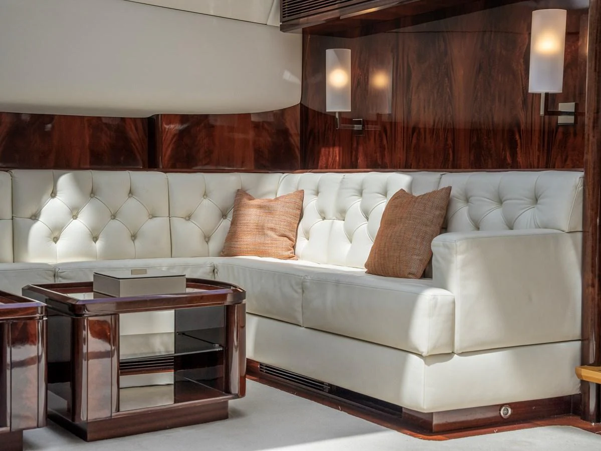 The salon features a luxurious white leather sectional sofa with rich wooden accents and soft lighting. aboard VALQUEST Yacht for Sale