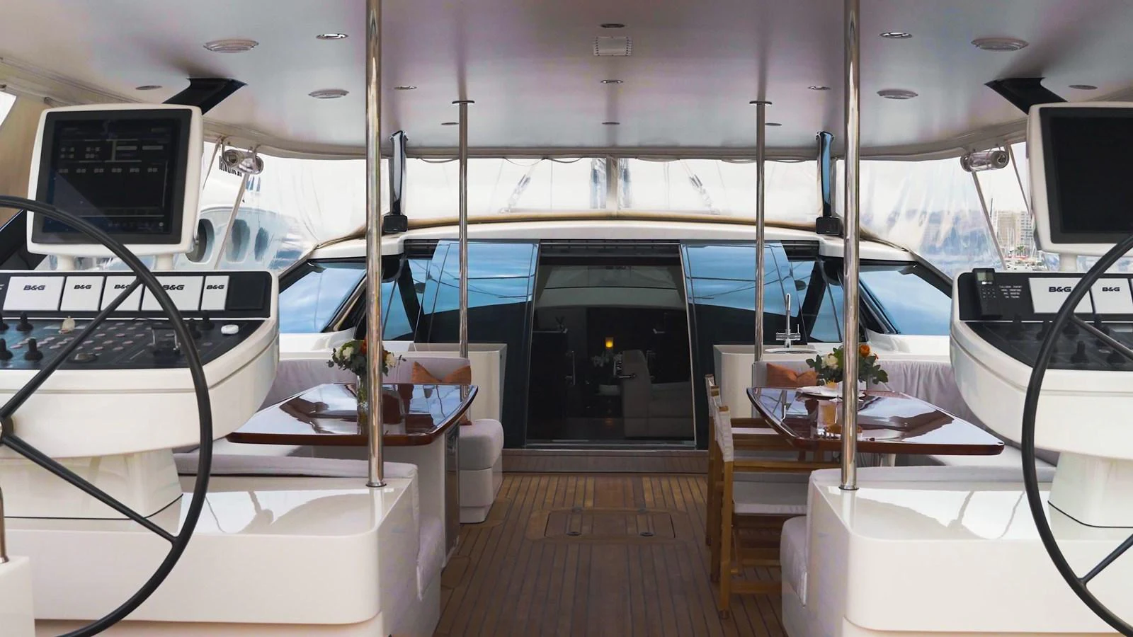 The yacht's cockpit features dual helm stations and a spacious seating area with elegant wooden tables. aboard VALQUEST Yacht for Sale
