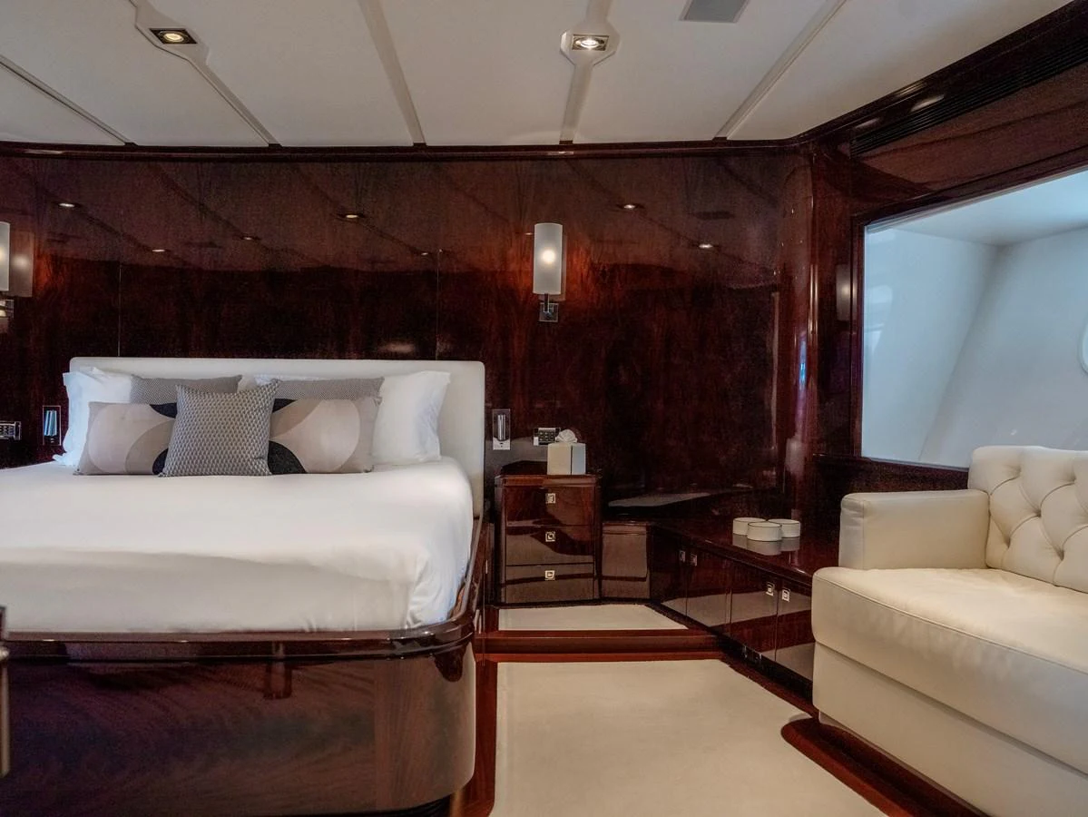 The master stateroom features a luxurious bed and elegant seating area with rich wood finishes. aboard VALQUEST Yacht for Sale