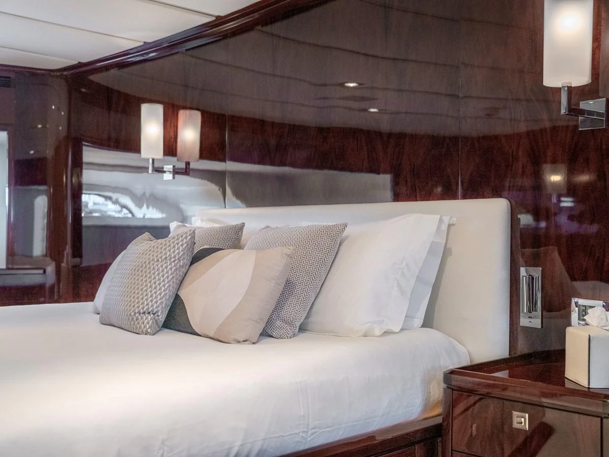The stateroom features a luxurious bed with plush pillows and elegant wood paneling. aboard VALQUEST Yacht for Sale