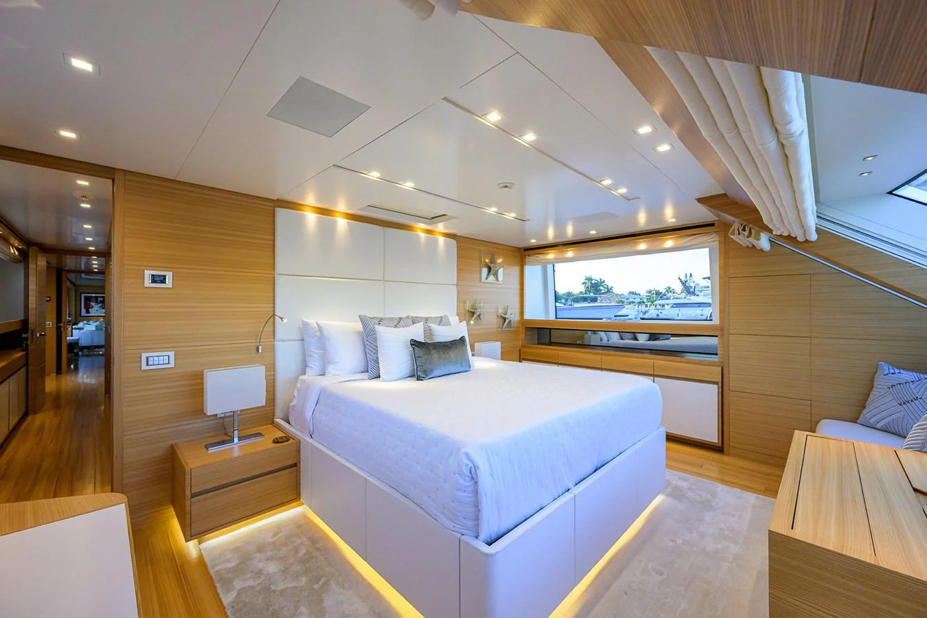 The master stateroom features a luxurious bed with ample natural light and modern wooden accents. aboard CHRISTINA Yacht for Sale