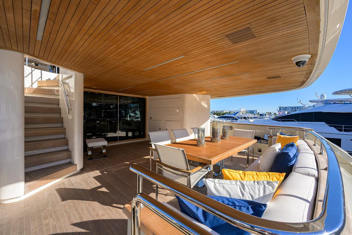 The aft deck features a stylish outdoor dining area with comfortable seating and a wooden table, perfect for alfresco meals. aboard CHRISTINA Yacht for Sale