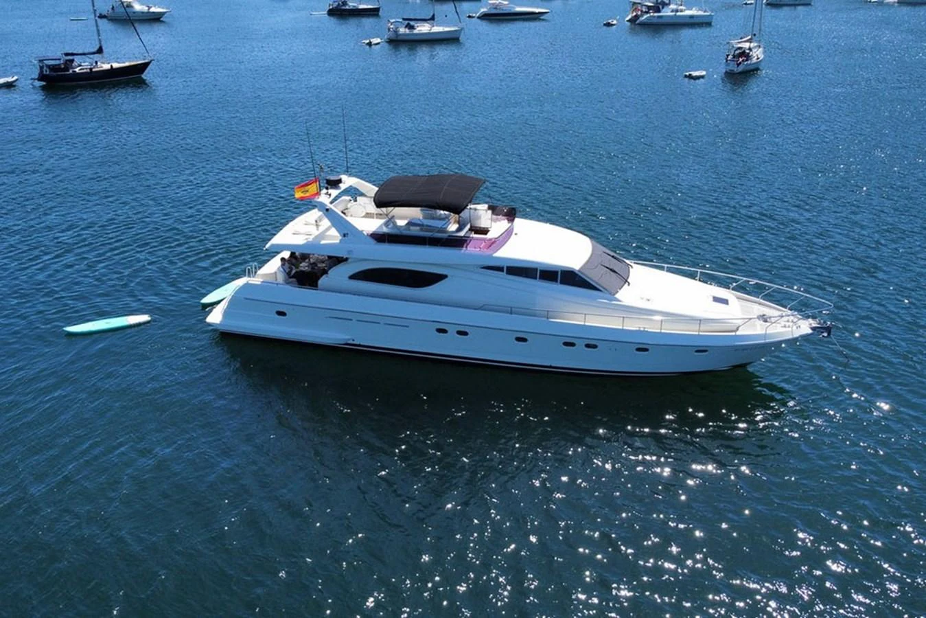 A sleek white yacht glides gracefully on calm blue waters, surrounded by other boats. aboard FERRETTI 70 Yacht for Sale