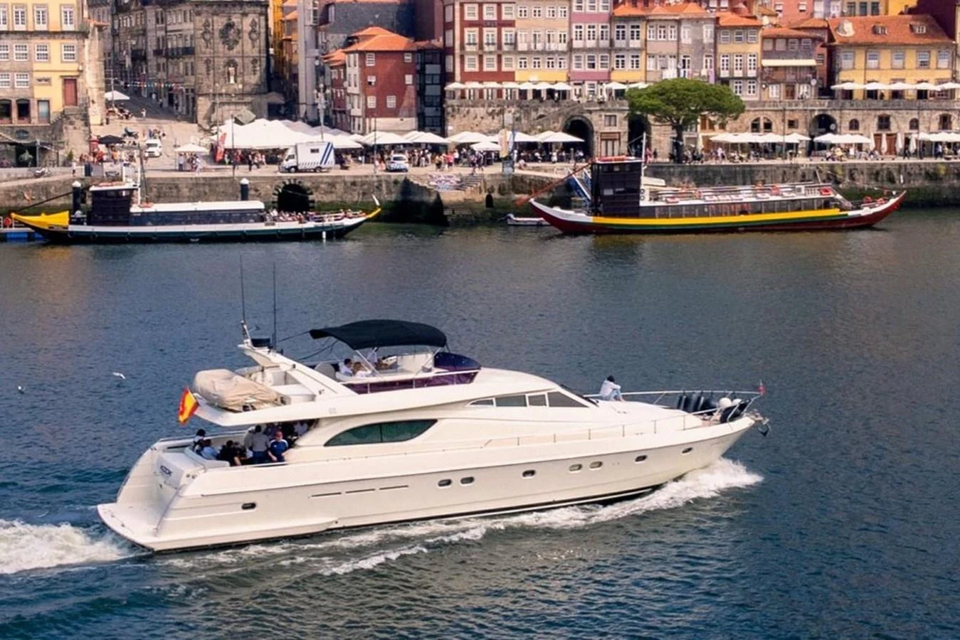 A sleek yacht cruises along a picturesque waterfront with historic buildings in the background. aboard FERRETTI 70 Yacht for Sale