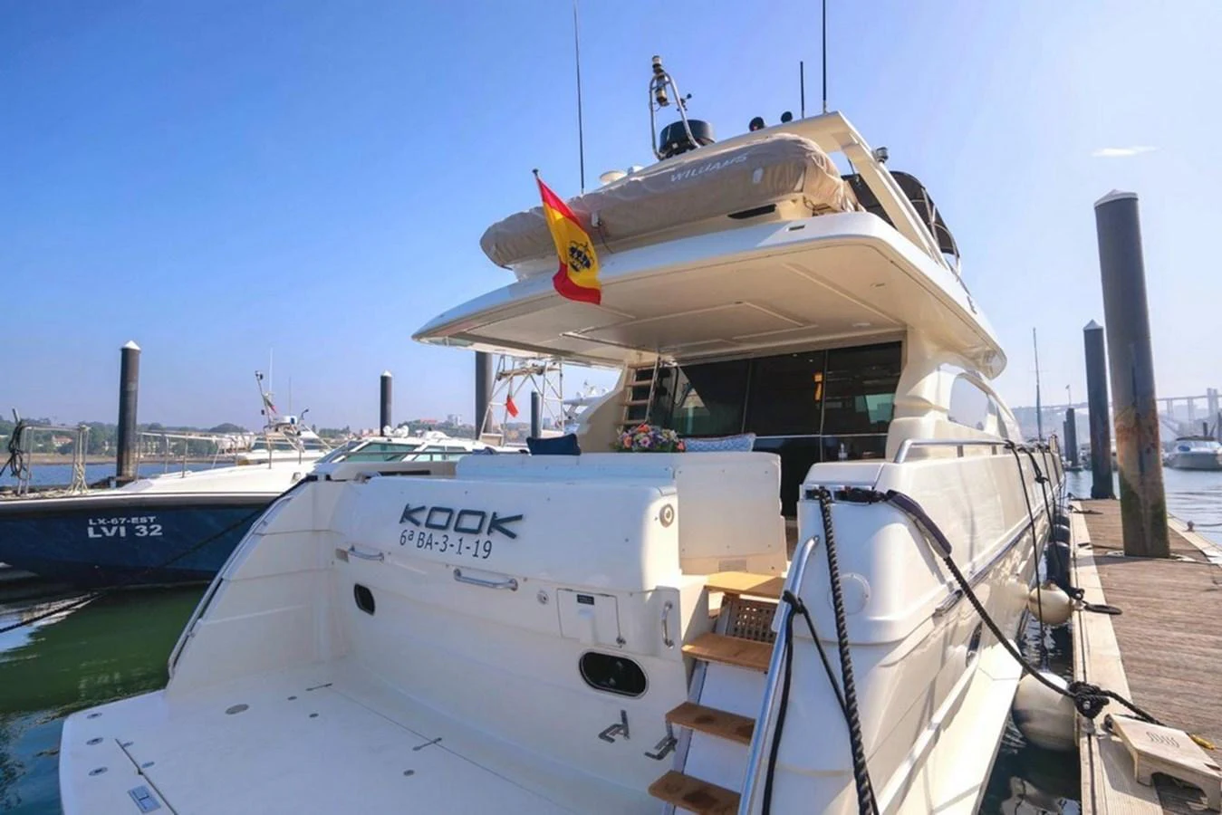 The yacht is docked at a marina, showcasing its spacious aft deck and inviting swim platform. aboard FERRETTI 70 Yacht for Sale