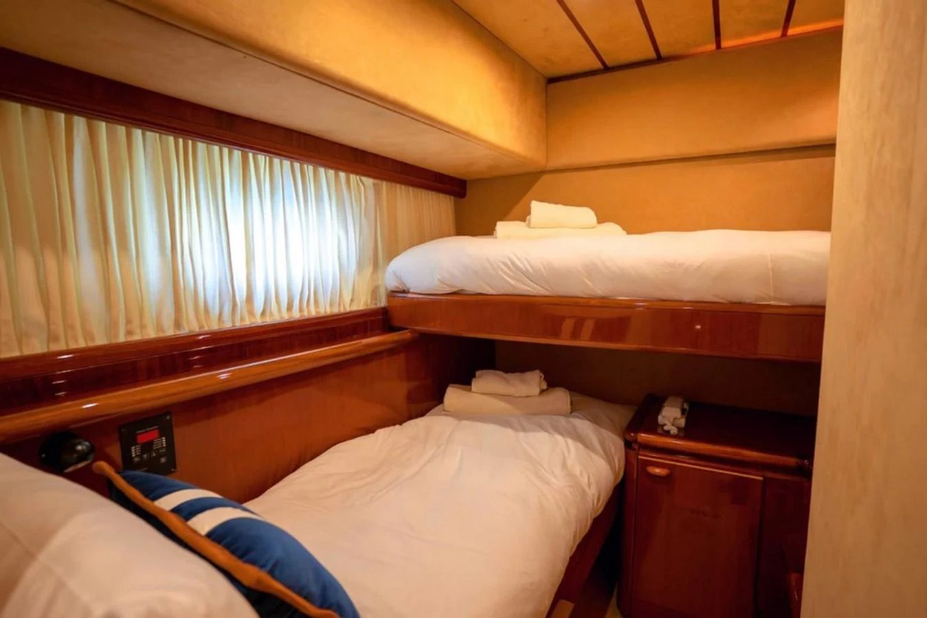 The cozy guest cabin features twin bunk beds with warm lighting and wooden accents. aboard FERRETTI 70 Yacht for Sale