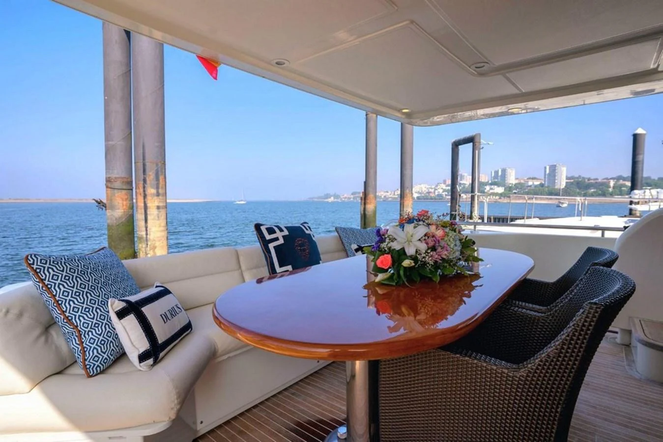 The aft deck offers a comfortable seating area with a polished wooden table and scenic views of the water. aboard FERRETTI 70 Yacht for Sale