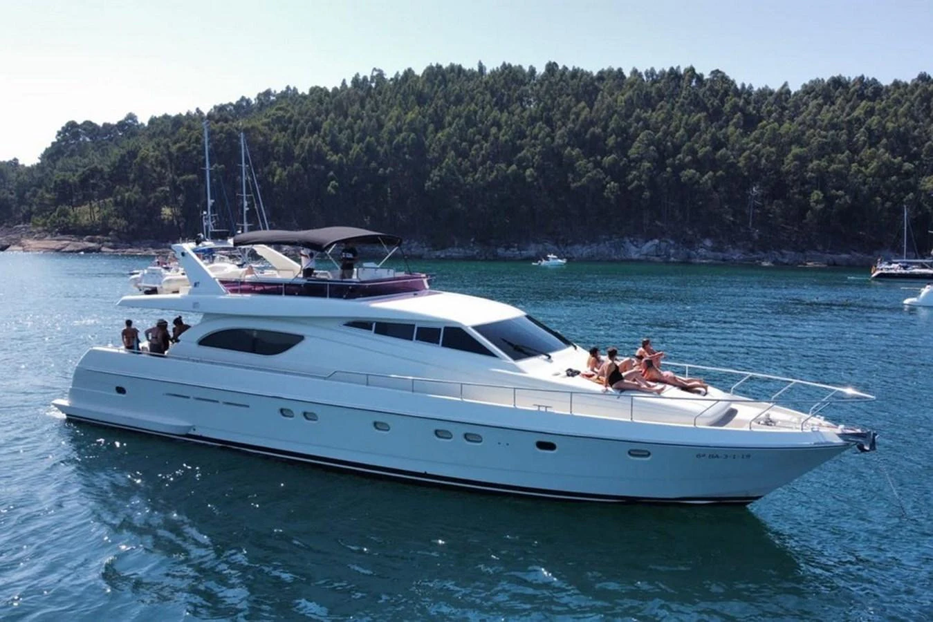 A sleek yacht cruises on calm waters with passengers enjoying the sun on the deck. aboard FERRETTI 70 Yacht for Sale